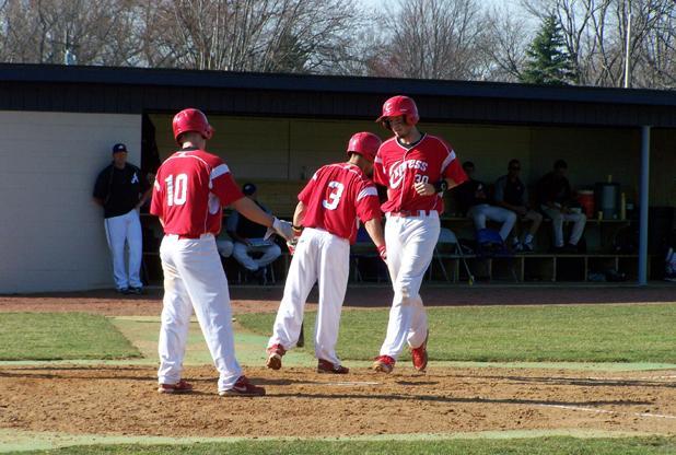 Above, Travis Tackett (30) is congratulated at home plate following his fourth inning, two-run homer that brought the Express within a run in the first game. Below, Sean Koerber is consulted by Express head coach Del Young, while Tackett listens. Photos by Rudy Yovich/Owens Sports Information