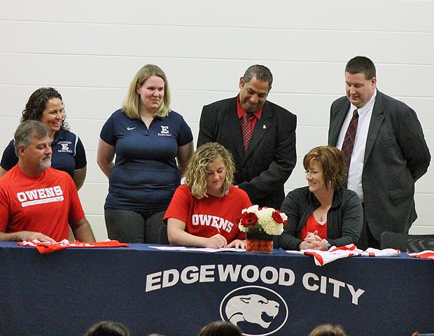 Maura Hackney, front center, is surrounded by her parents (Timothy and Chris), future coaches (Mike Llanas and Stephen Perry) and current coaches (Andrea Swartz and Britney Hamilton) as she signs a letter of intent to play women's basketball for the Express next season. She becomes the second member of the 2013-14 freshmen class. Photo by Nicholas Huenefeld/Owens Sports Information